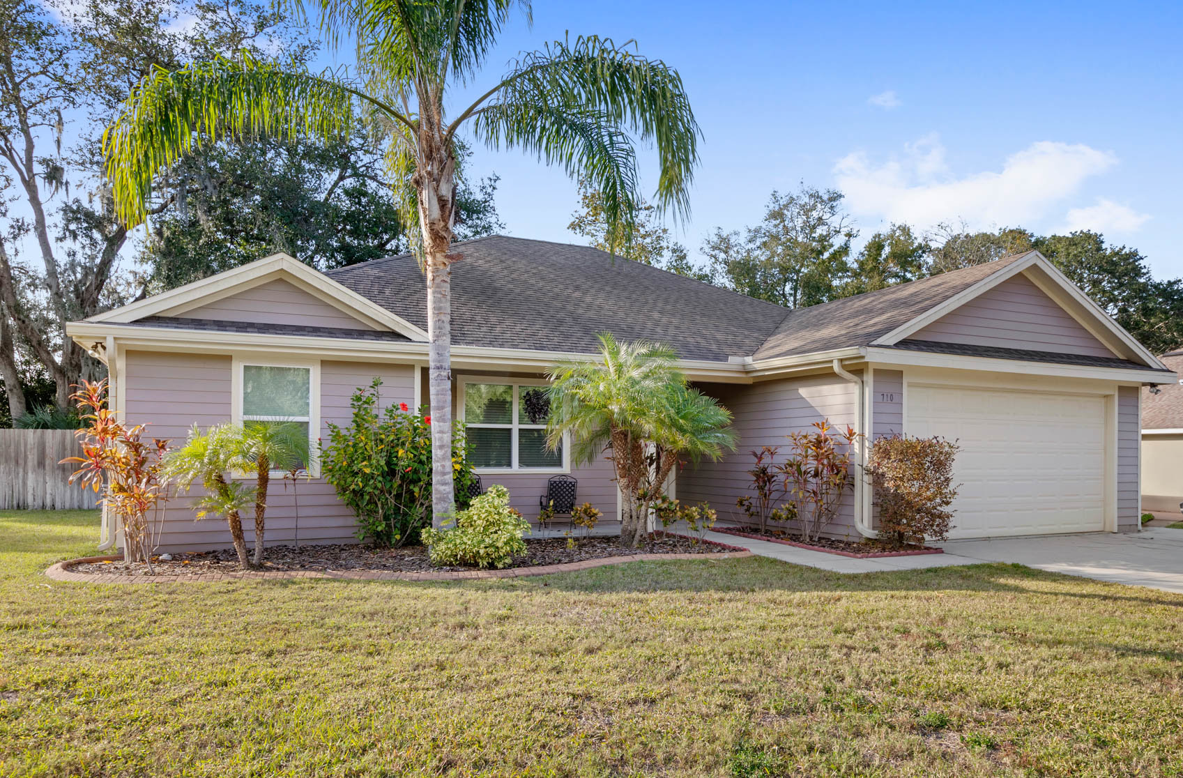 front of one story home with white and purple paint and brown roof